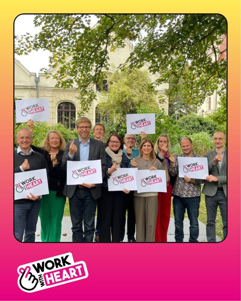 Gruppenbild mit Mitgliedern des BeB-Vorstands, die Schilder mit dem Kampagnenlogo #WorkWithHeart halten